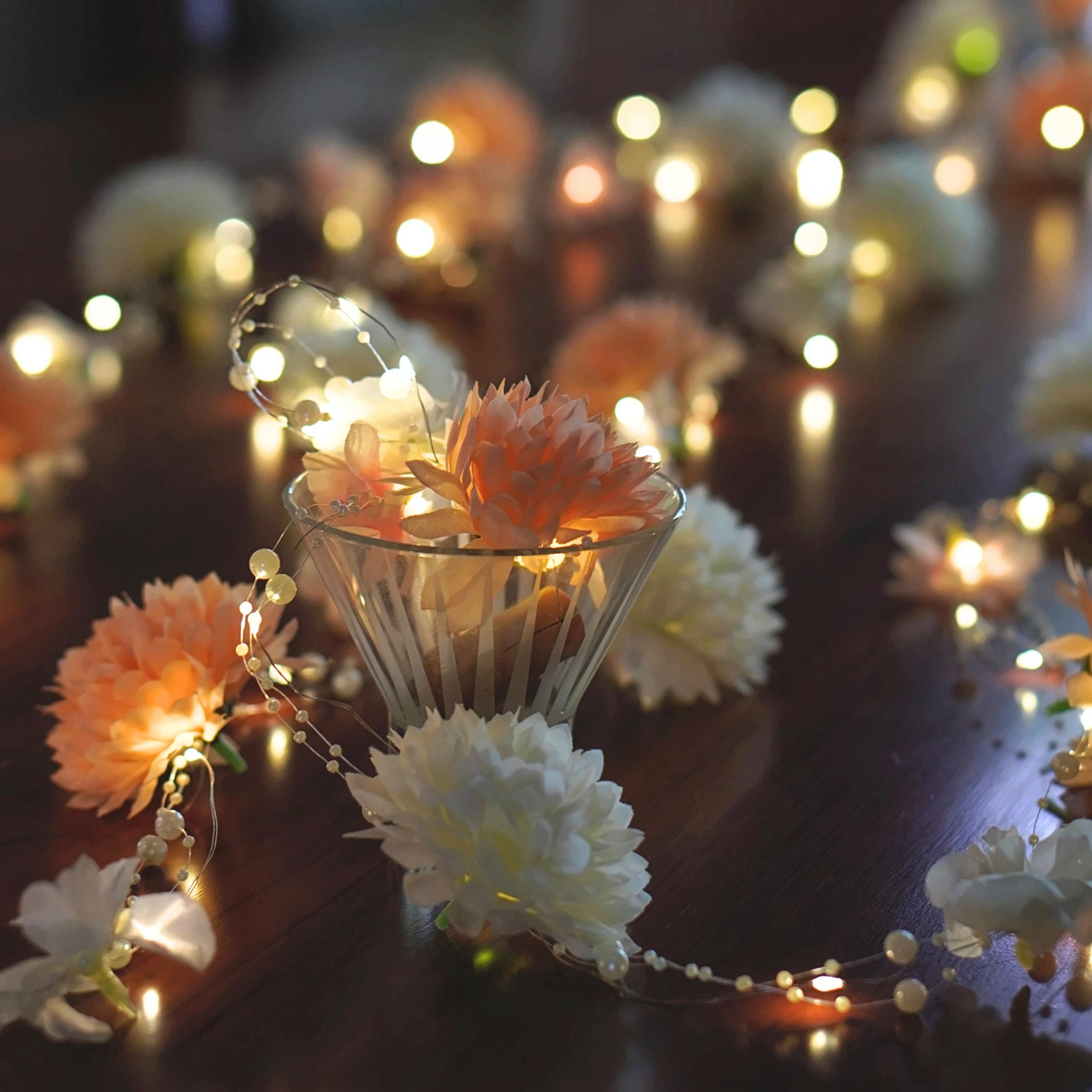 Macro of the toran flowers and warm fairy lights with a glass