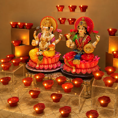 Red LED diyas glowing in rows beside the idols with more raised on gold boxes behind
