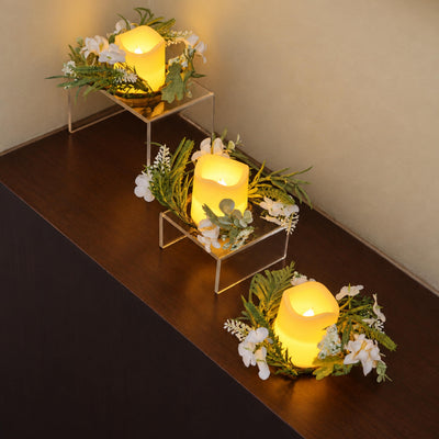 Three Amalfi Candle Rings glowing on a dark woven surface