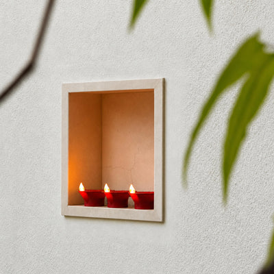 Three big flame LED diyas glowing in a single wall niche