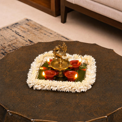 Big flame LED diyas around a brass lamp on a mirrored tray with a flower border