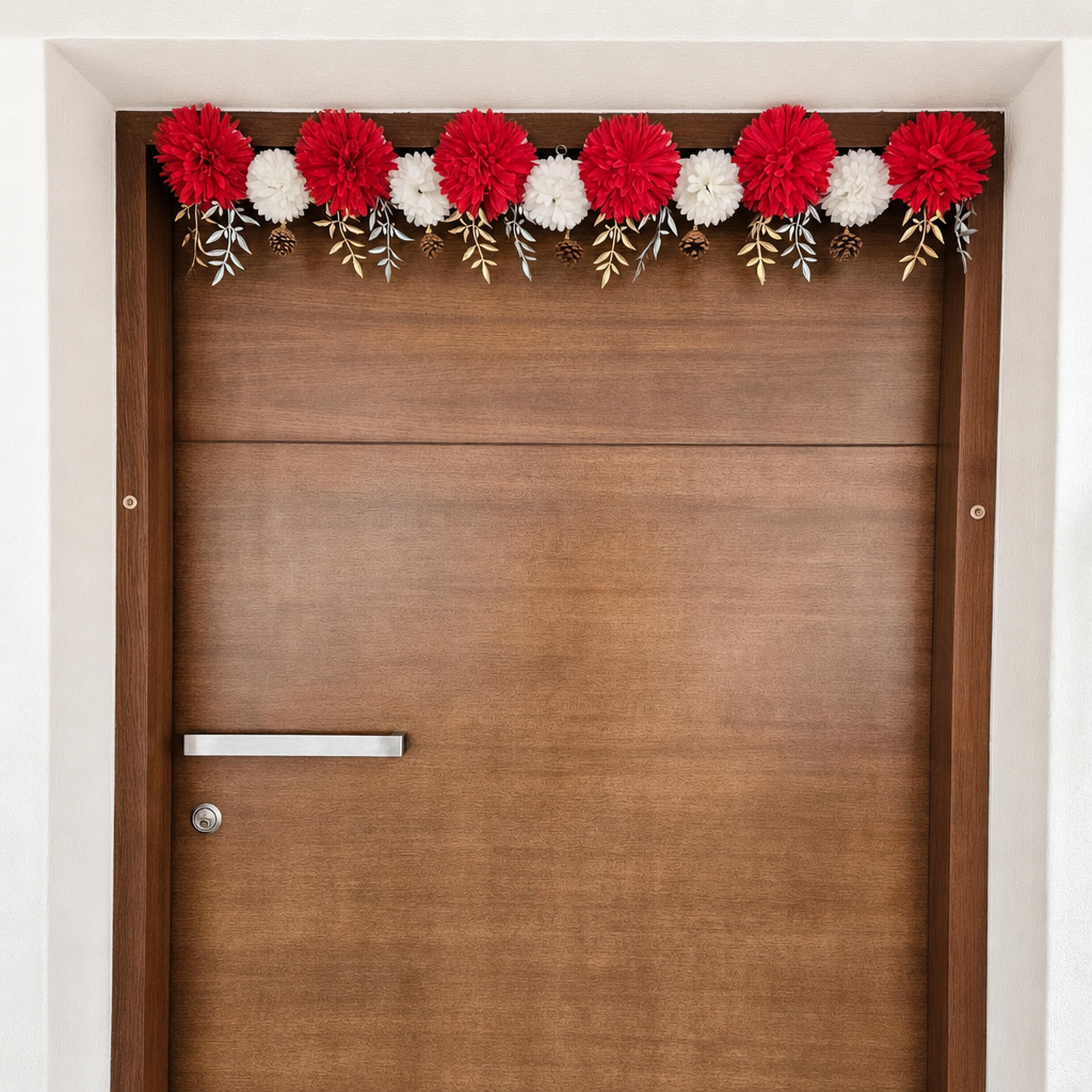 Red and white flower toran with gold leaves across the top of a wood door