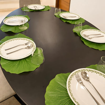 Lotus leaf place mats with plates on a dark oval dining table